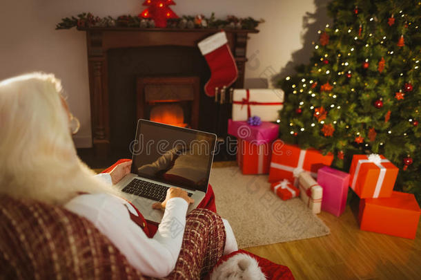 圣诞<strong>老人</strong>坐在<strong>扶</strong>手椅上用笔记本电脑
