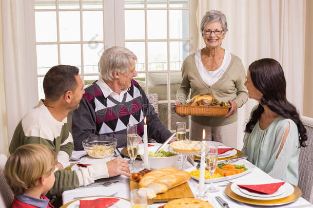 奶奶和家人在餐桌上拿着烤火鸡