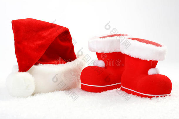 白色背景前雪地上的圣诞老人帽子和靴子
