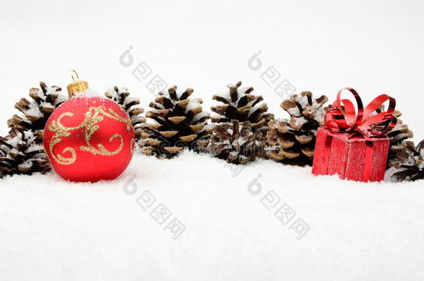 雪地上的两个红色圣诞小饰品在雪地上排队