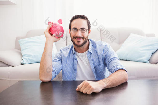 快乐的男人摇着粉红色的小猪罐