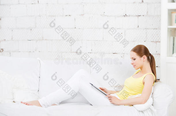 坐在沙发上拿着数码平板电脑的女孩。乔迁之喜。