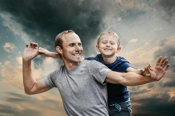 冷色调天空上快乐的微笑着的儿子和父亲的肖像