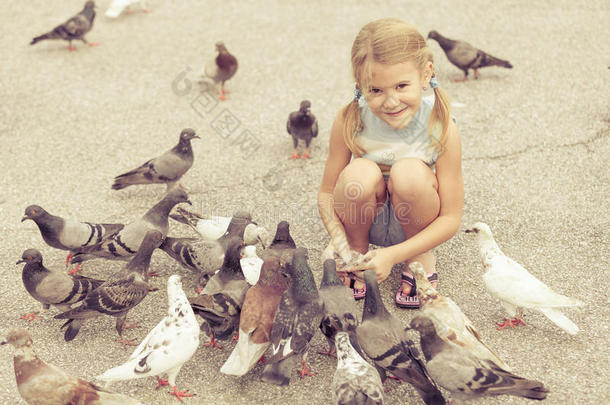 小女孩在公园里喂鸽子
