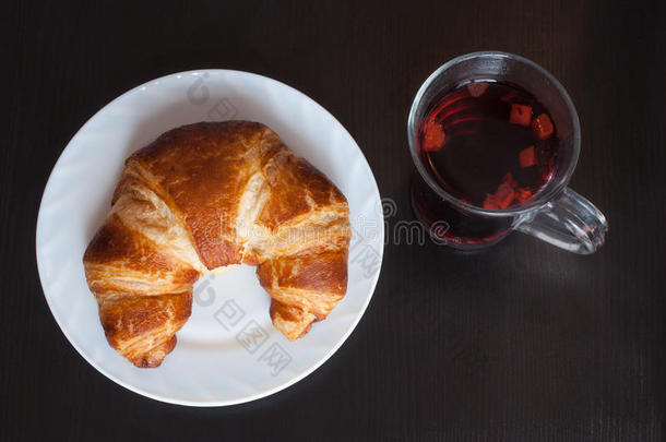新鲜可口的巴伐利亚羊角面包，白色盘子和一杯水果茶在木质背景上