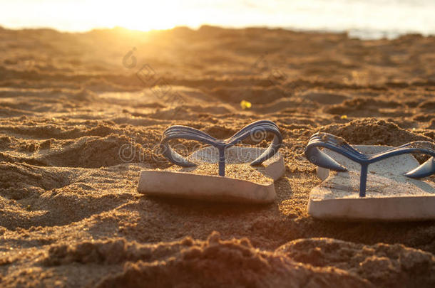 沙滩上的沙滩上有白色的拖鞋，阳光从后面照耀着