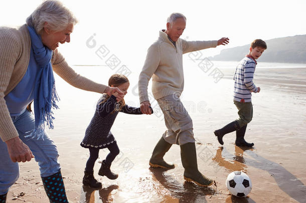 爷爷奶奶和孙子孙女在沙滩上踢足球