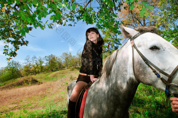 骑着马的漂亮女孩在森林里散步