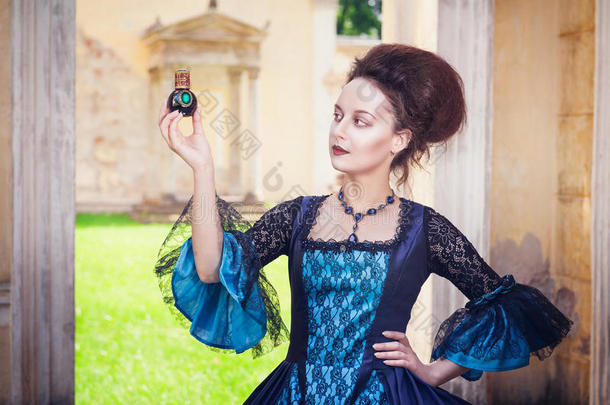 美丽的女人穿着中世纪的衣服，带着香水瓶