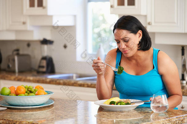 厌倦了超重的女人在厨房吃健康的饭菜