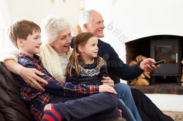 爷爷奶奶和孙子们坐在沙发上看电视
