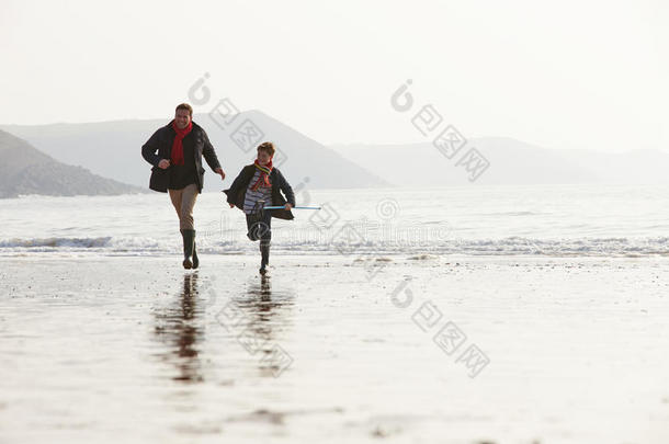 父子俩拿着渔网在冬天的沙滩上奔跑