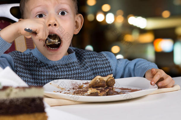饥饿的小男孩<strong>狼吞虎咽</strong>地吃下一片蛋糕