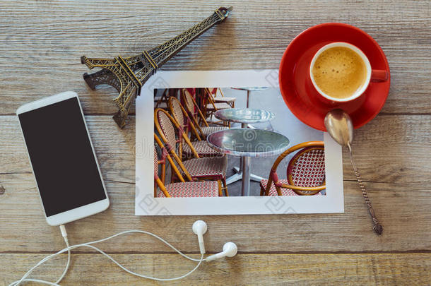 巴黎餐厅的照片在木制<strong>桌子</strong>上，有咖啡杯和智能手机。<strong>俯视</strong>图