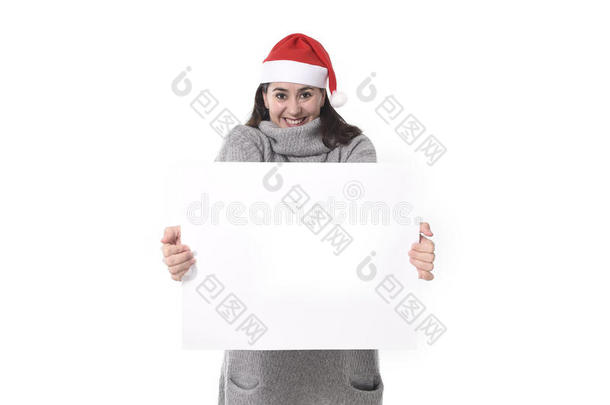 年轻可爱的拉丁女人戴着圣诞帽手持空白广告牌