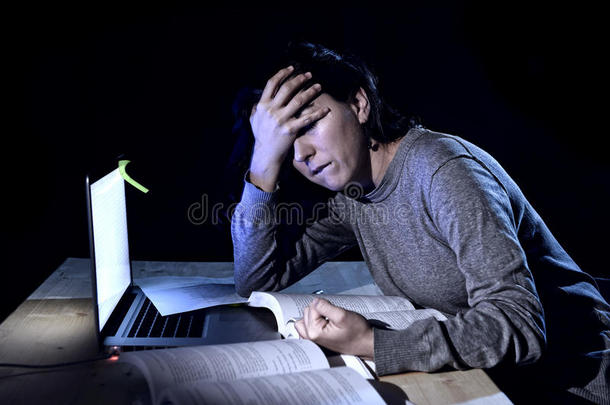 年轻绝望的女大学生考试压力大，深夜拿着书和电脑学习