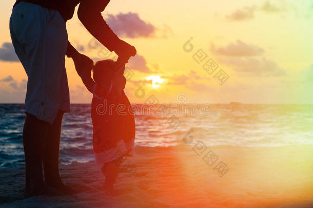 父亲和小女儿在日落海滩散步