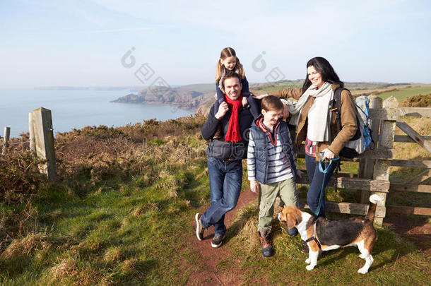 一家人带着狗沿着海岸<strong>小路散步</strong>