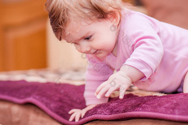 小婴儿躺在毯子上露出舌头。