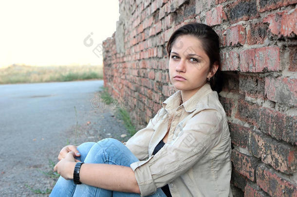 一个伤心的小女孩在砖墙旁