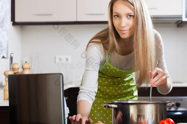 金发女人用笔记本电脑煮汤