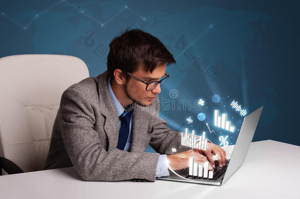 年轻人坐在办公桌旁，用笔记本电脑打字，上面有图表和