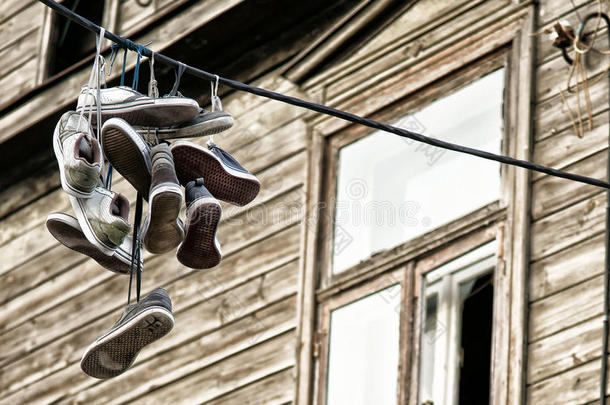 旧运动鞋扔在黑色电缆上，背景是家