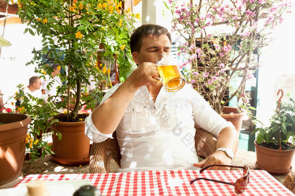 一个年轻人在炎热的天气里在餐厅夏日露台喝啤酒