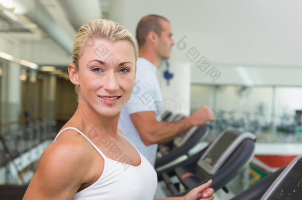 健身夫妇在健身房跑步机上跑步