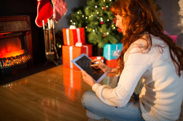圣诞节红发女人坐在地板上用平板电脑