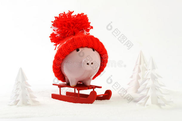 红帽子的小猪盒站在雪地上的红色雪橇上，周围是积雪覆盖的树木