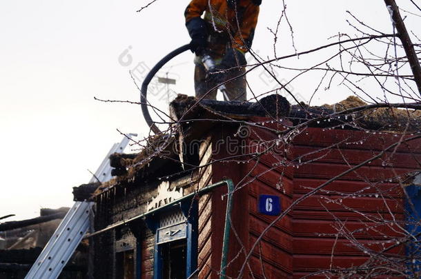 <strong>消防队</strong>员在<strong>灭火</strong>后向木屋屋顶浇水。