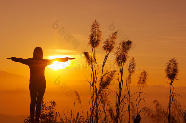 夕阳西下的剪影让年轻女人感<strong>受到</strong>自由和放松