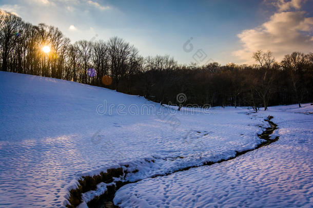 巴尔的摩乡下一片白雪皑皑的田野上的小溪上的夕阳