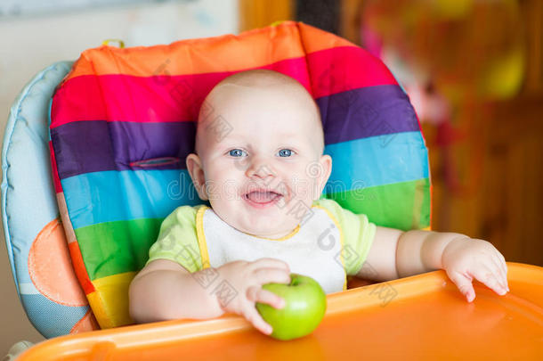 可爱的宝宝在高脚椅上吃苹果