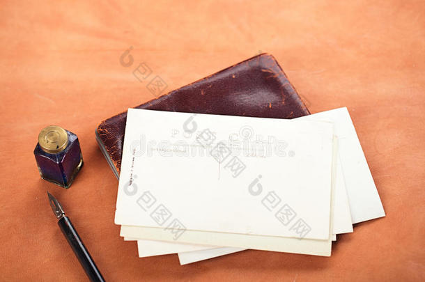 一堆复古明信片和墨水笔，墨水壶放在皮革桌上