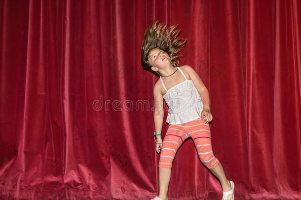 快乐，快乐的<strong>小女孩</strong>看着自己的头发运动，当她<strong>奔跑</strong>，跳舞在黑暗的红色窗帘背后的舞台上