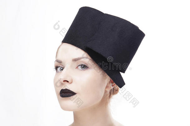 华丽的金发女人模型，蓝色眼睛和黑色口红，戴着时尚设计的黑色独特帽子/头饰