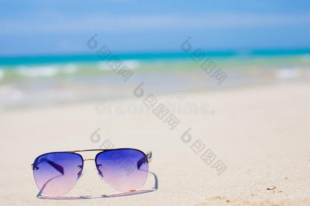 蓝色太阳眼镜躺在热带沙滩上。