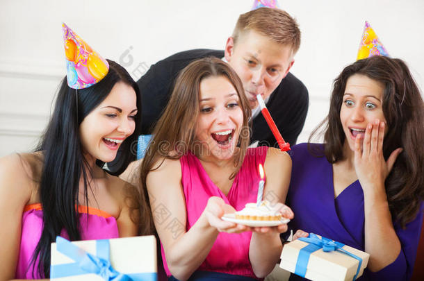 一个<strong>女孩</strong>在聚会上围着朋友看<strong>生日蛋糕</strong>