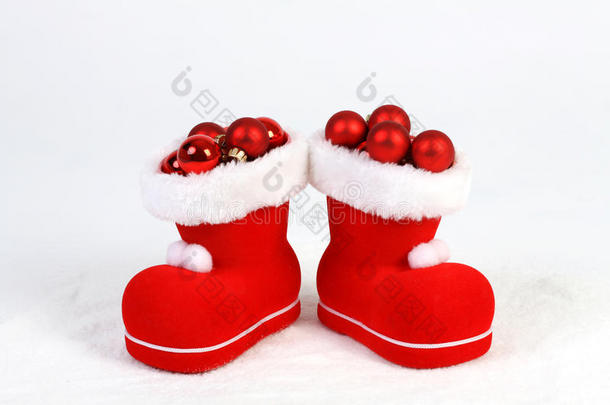 圣诞老人帽子和靴子，白色背景前的雪地上有红色和哑光圣诞球