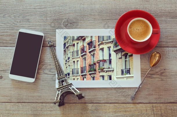 巴黎建筑物的照片，在木制的桌子上放着咖啡杯和智能手机。俯视图