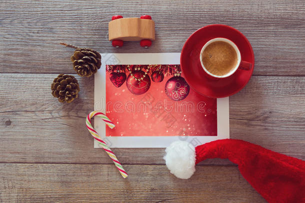 圣诞假期装饰的照片在木制<strong>桌子</strong>上，有咖啡杯和圣诞帽。<strong>俯视</strong>图
