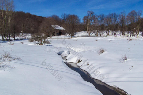 雪原上有小溪和山脉的乡村谷仓