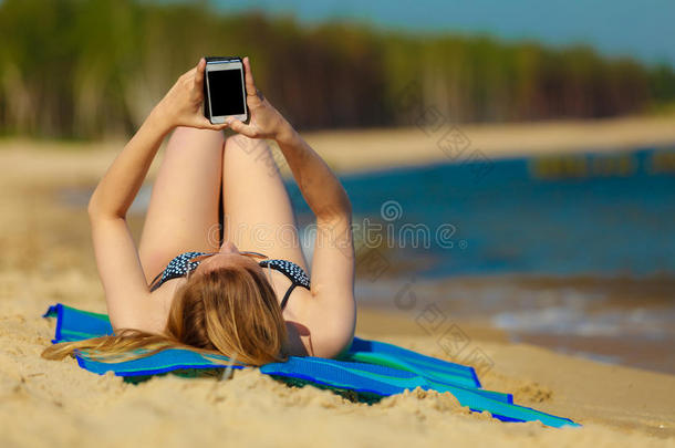 <strong>暑假</strong>女孩在海滩上用电话晒太阳