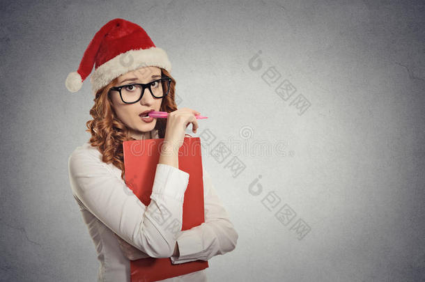 戴着圣诞帽的女人在摄影棚摆姿势，想着礼物的点子