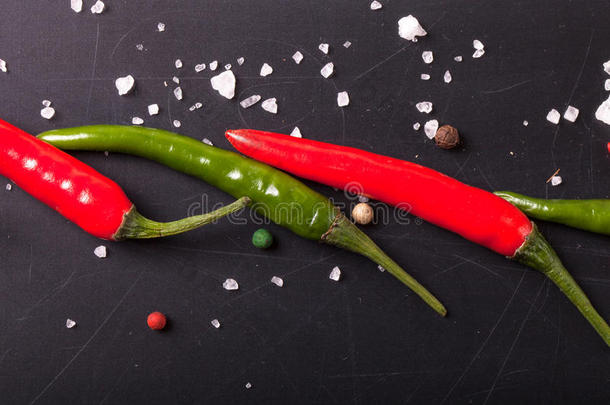 红、绿辣椒，粗盐放在黑板上。色调