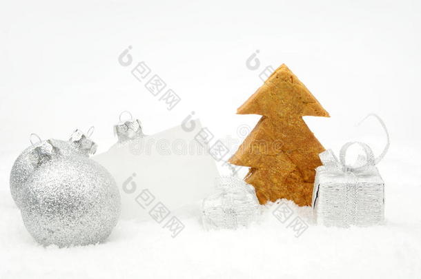 雪地上的银色圣诞装饰，带有祝福卡和饼干