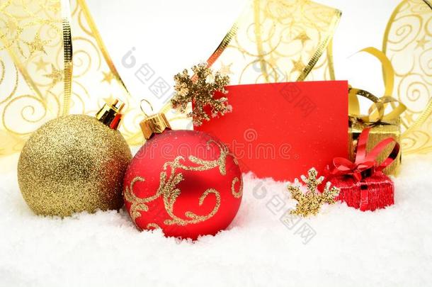 金色和红色的圣诞装饰在雪地上，上面有祝福卡