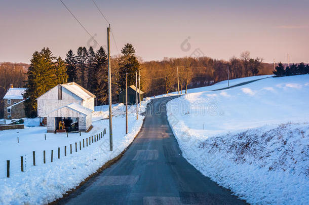在宾夕法尼亚州约克县农村，穿过被雪覆盖的农田的乡村公路。